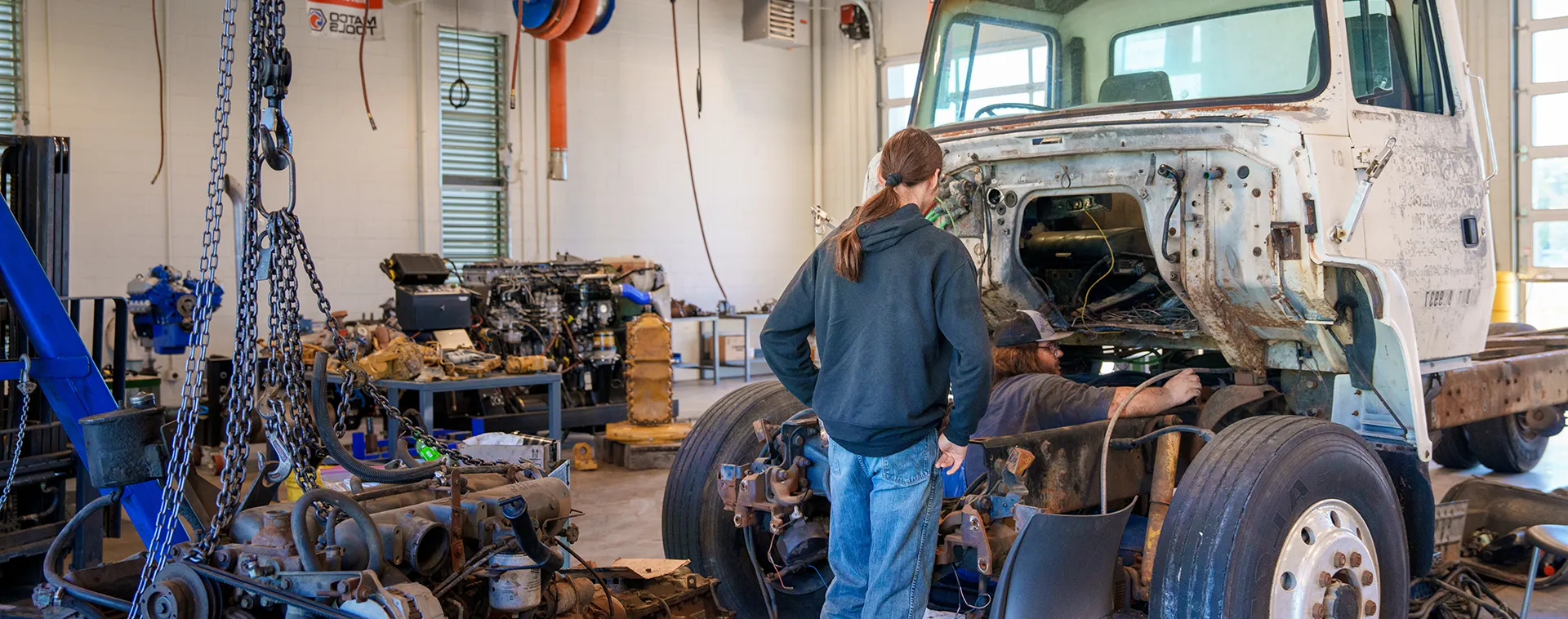 Students work on a truck chassis and cab in a heavy equipment technology training shop.