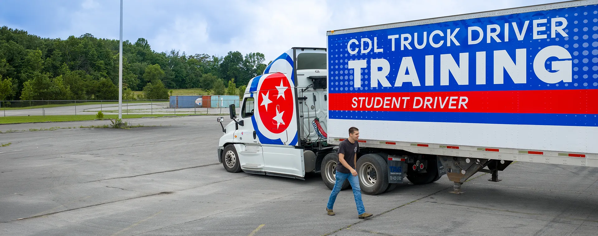 CDL truck driver training tractor-trailer with Tennessee branding parked on a training lot as a student walks beside it.