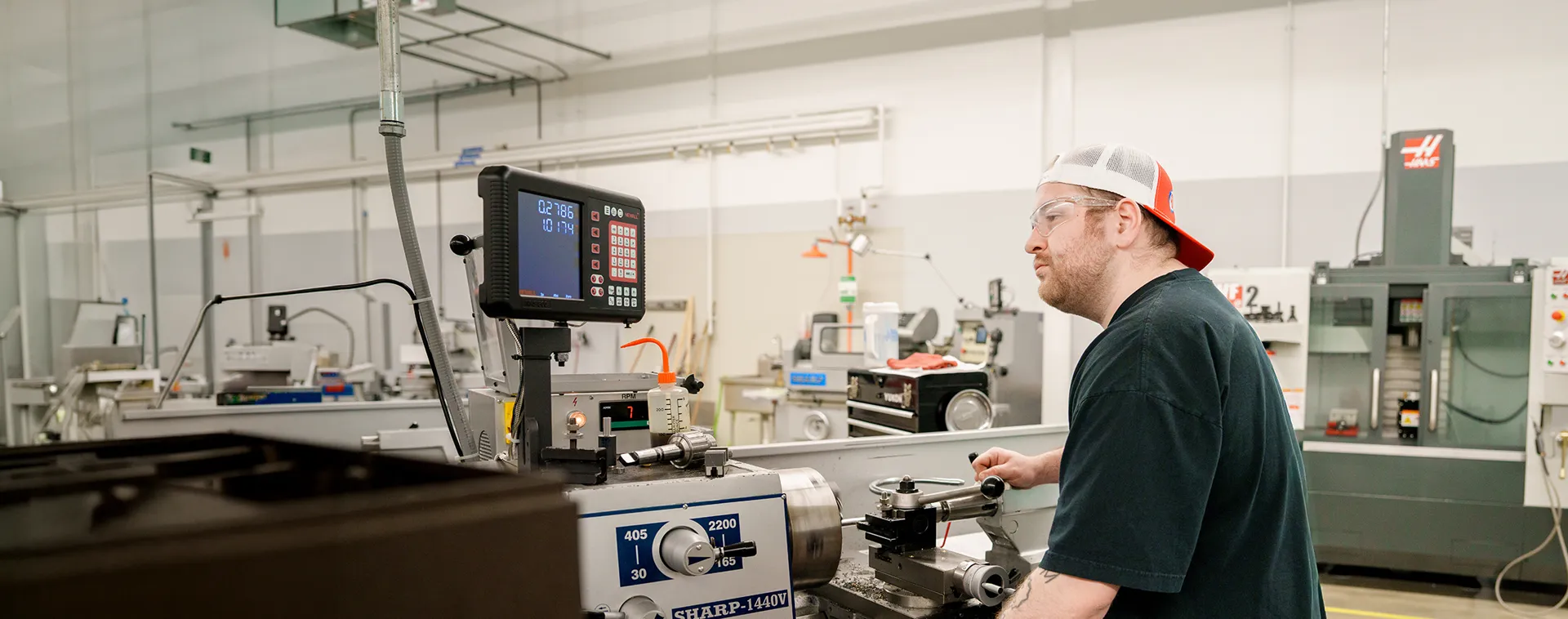 Student operates a metal lathe with a digital readout in a machine tool and machining lab.