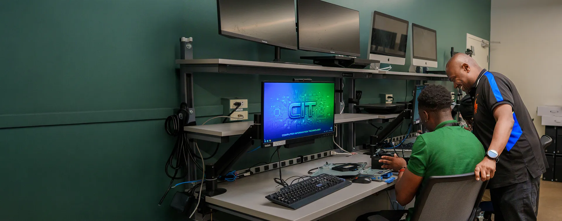 Student works at dual monitors displaying design software in a computer-aided design classroom.