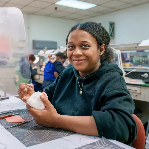 Student holds a dental model at a workstation in a dental laboratory classroom.